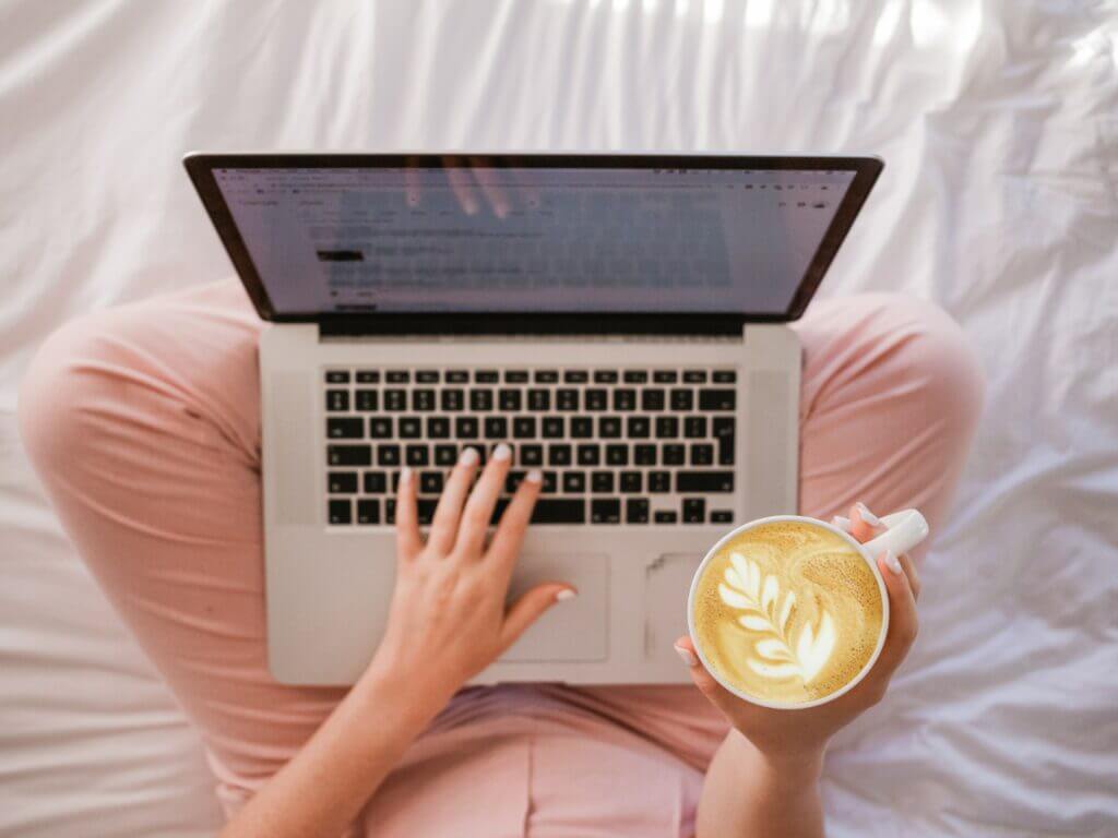 Woman with coffee and Mac laptop creating blog content