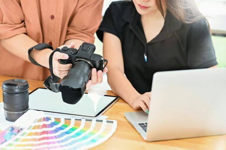 man and woman looking at camera with color palettes and computer. Coming up with content creation ideas